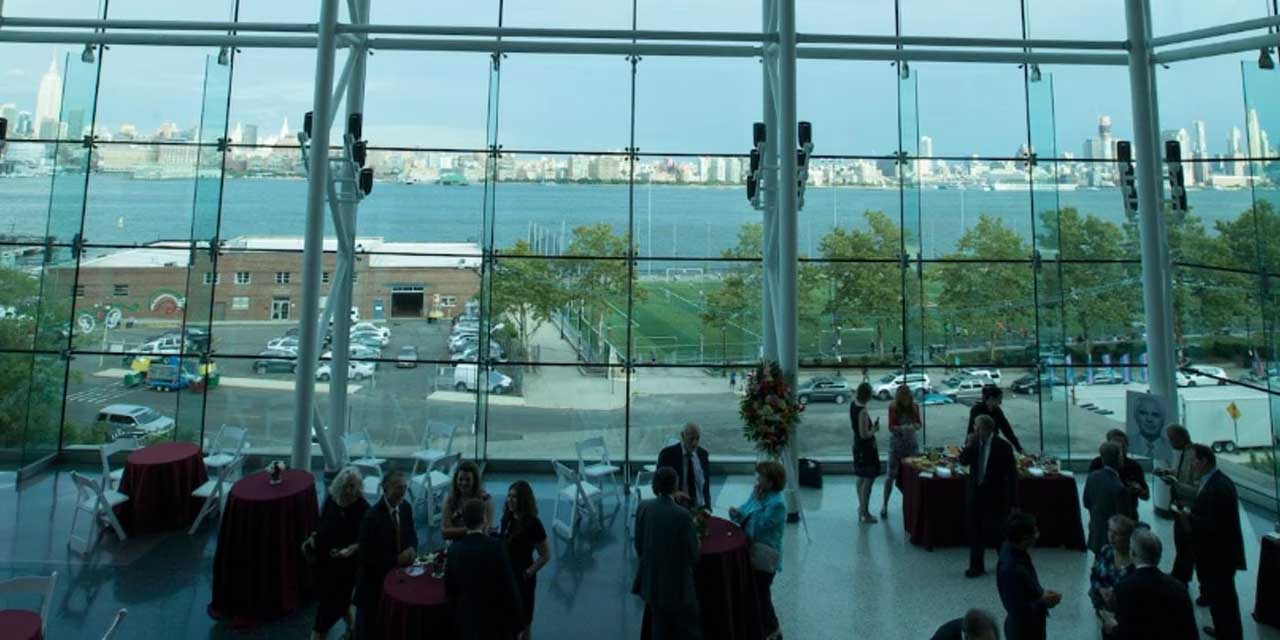 A Stevens alumni event inside a glass campus building with views of the New York City skyline.
