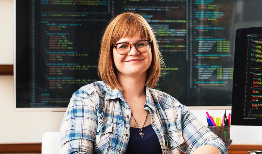 Student sitting in front of digital board and smiling.